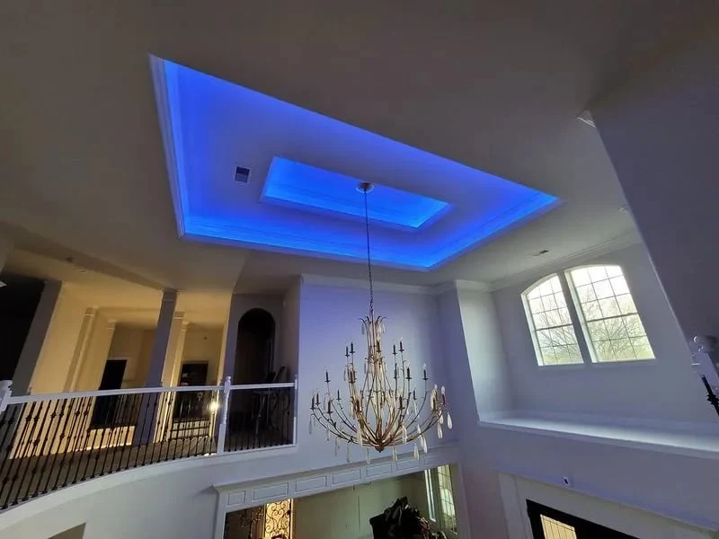 Custom architectural blue LED cove lighting and high-ceiling chandelier in Richmond TX